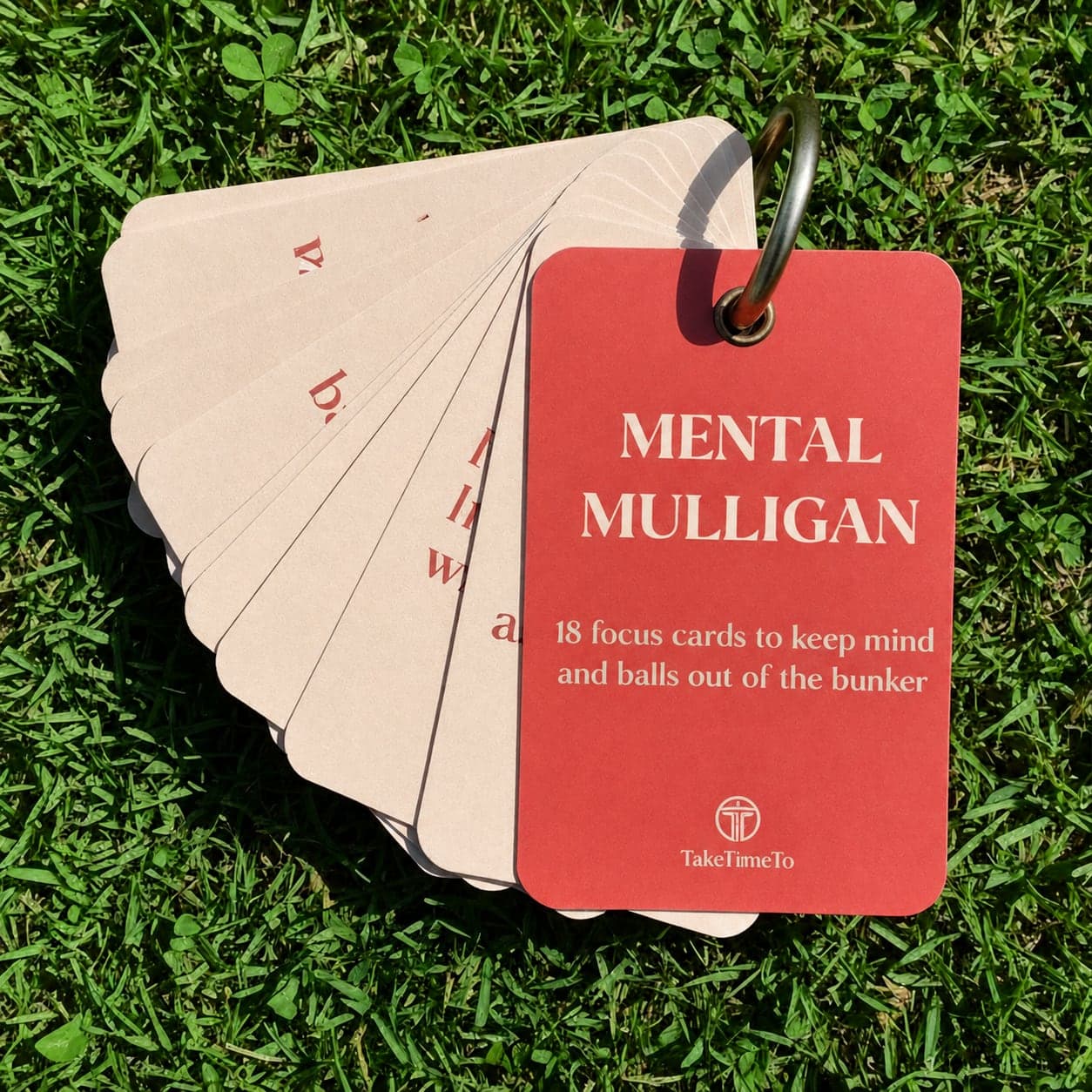 The Mental Mulligan deck fanned open on its ring, resting on the grass